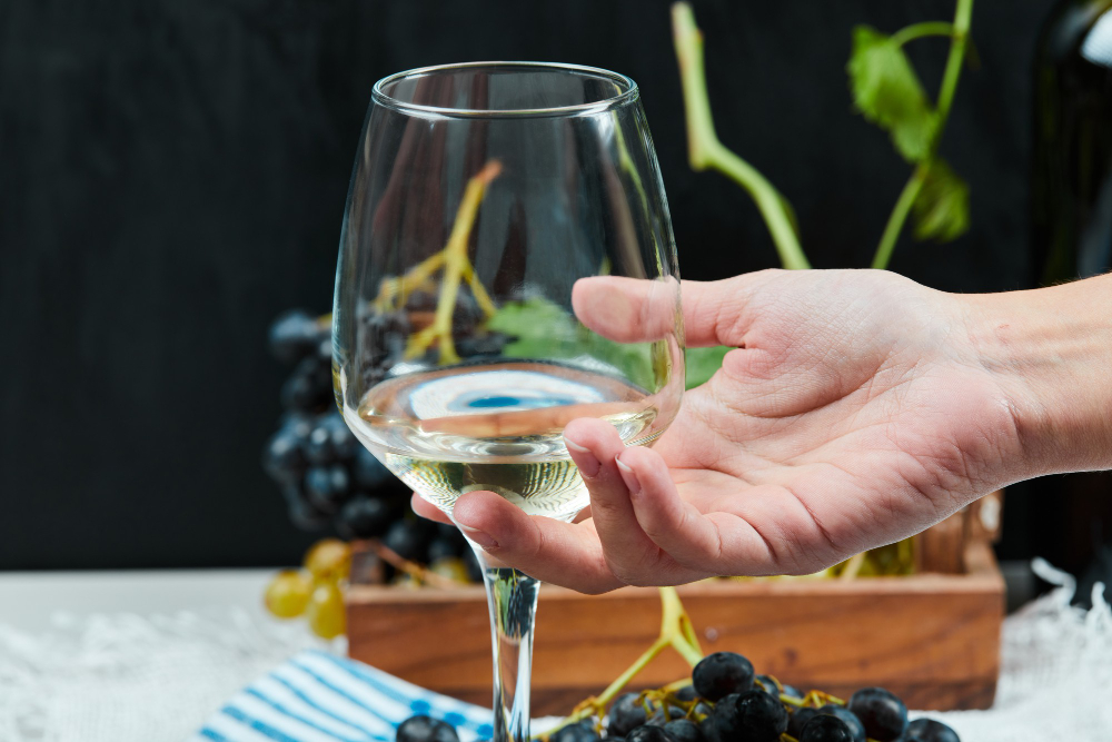 Mano sujetando copa de vino blanco