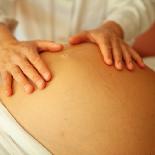 Reeducación postura global. Fisioterapeuta en Valderrobres apoyando sus manos en un vientre de una mujer embarazada.